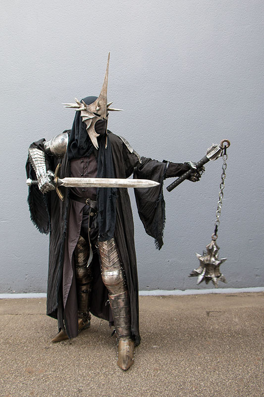Une photo d'un cosplayeur habillé en Sauron du Seigneur des anneaux. Il tient une épée et un fléau d'arme.
